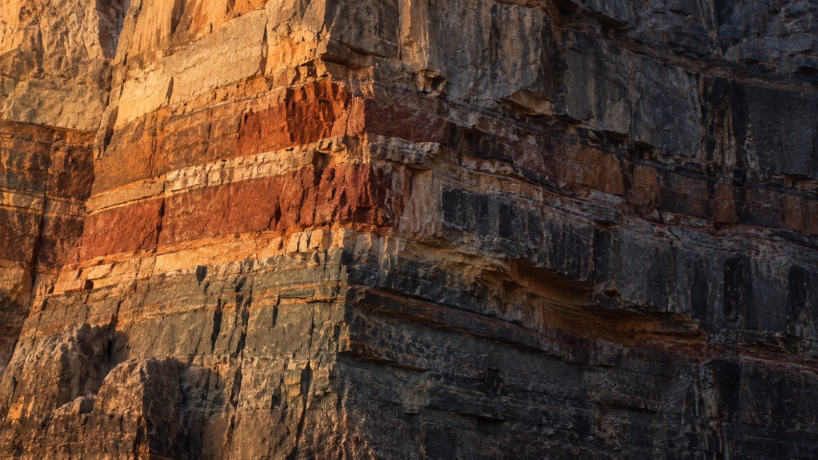Warm first light across an Algerian stone face at monumental scale